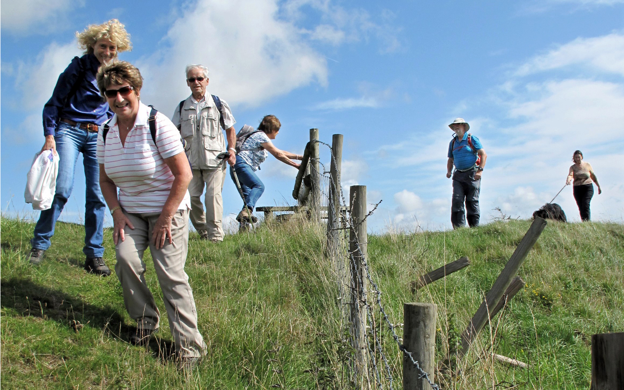 Group of Wednesday Walkers negotiating a fence